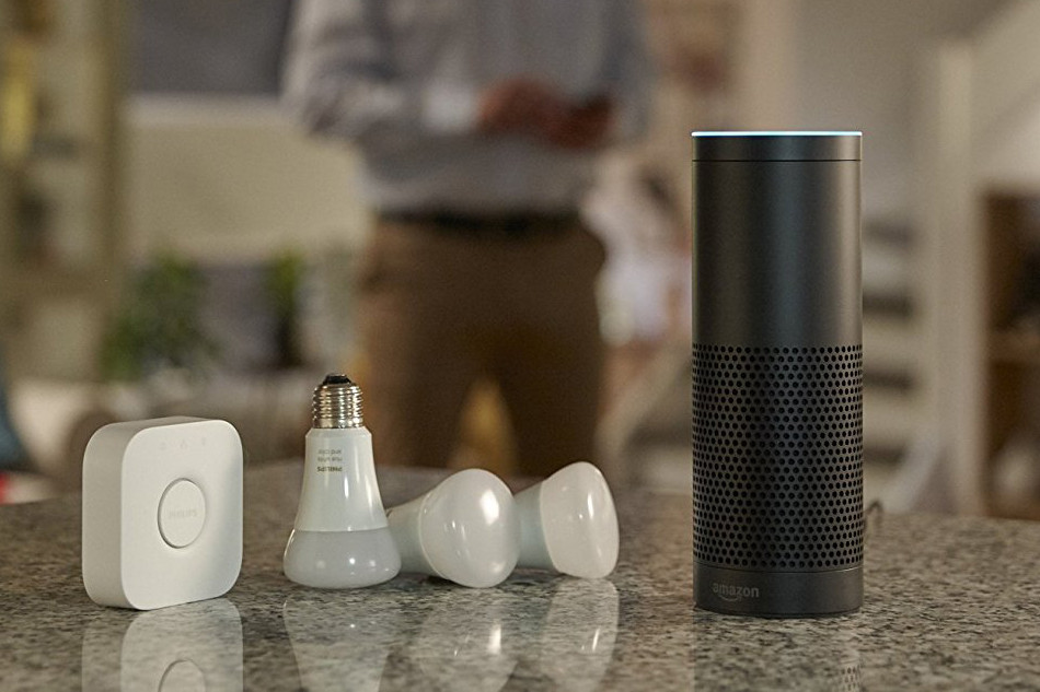An image of an Echo on a counter top next to a few Hue bulbs